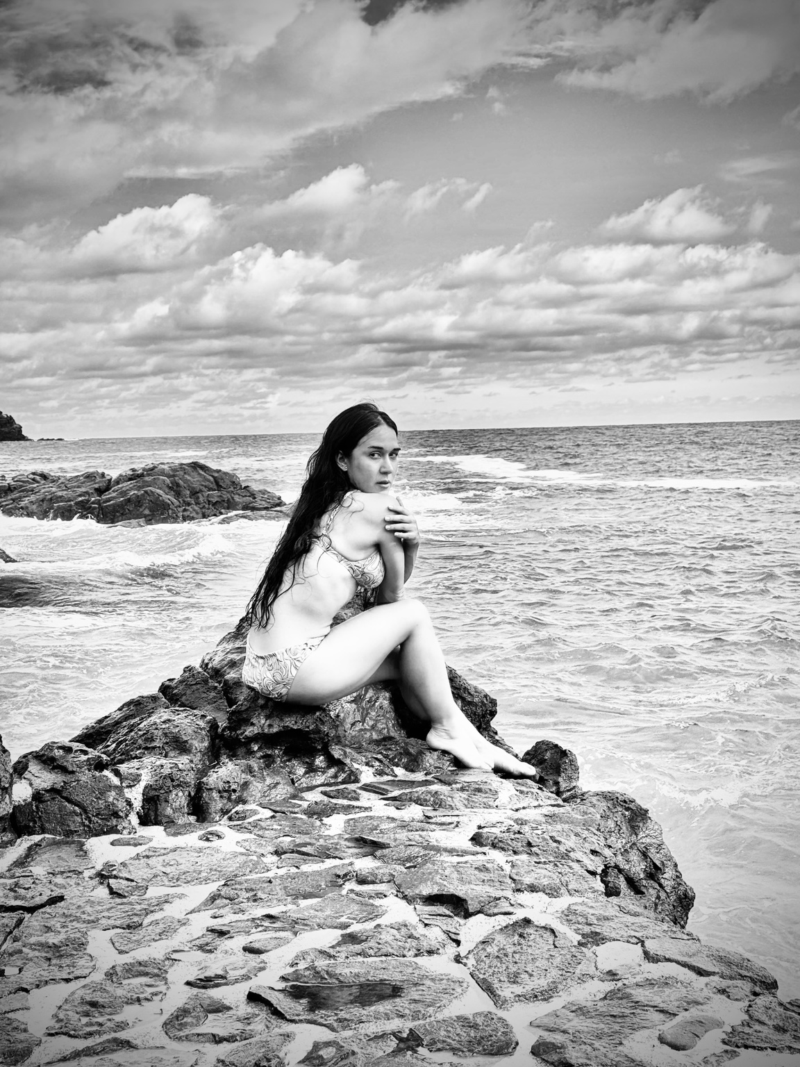Gabie Rainfall seated on a rock beside the sea